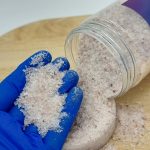 بسته بندی خوابیده رو زمین نمک صورتی (هیمالیا) و مقداری نمک در دست گرفته شده جهت بررسی کیفیت نمک