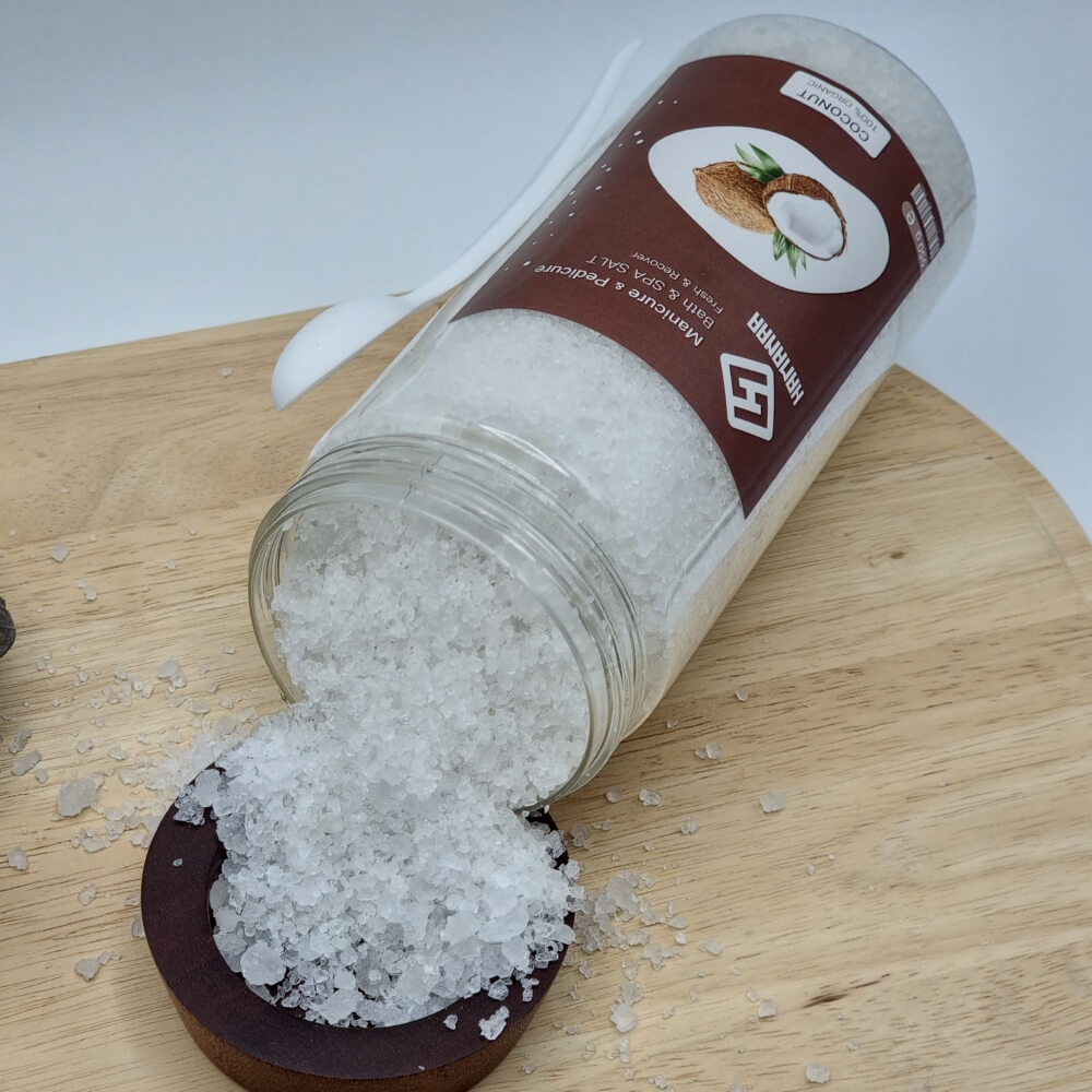 نمک سفید رنگ بیرون ریخته شده از بسته بندی نمک حمام در ظرف چوبی با عصاره نارگیل از نمای بالا