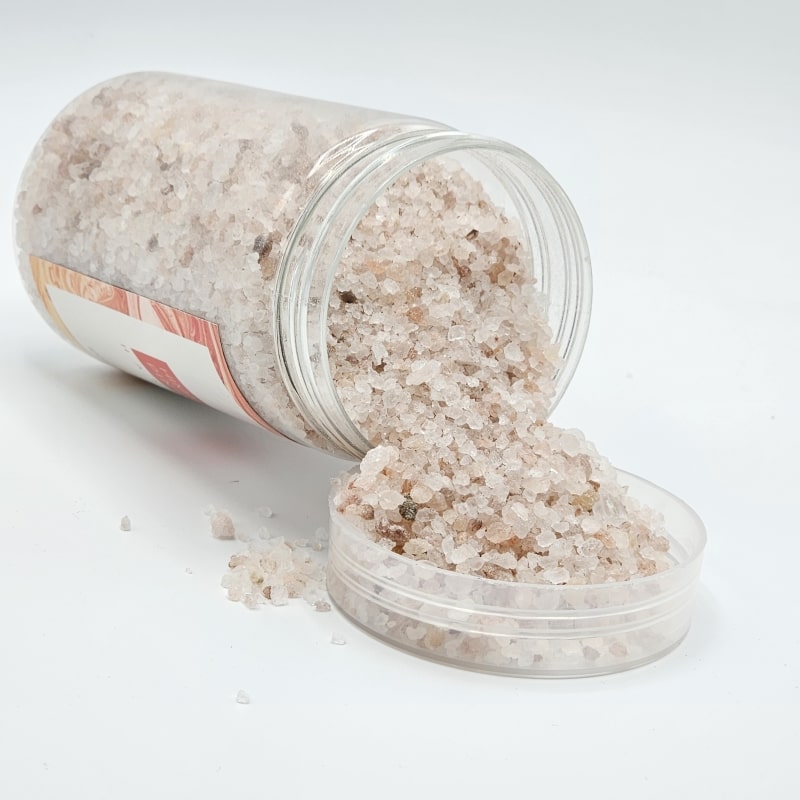 نمک هیمالیا درون ظرف ریخته شده به همراه دانه های نمک